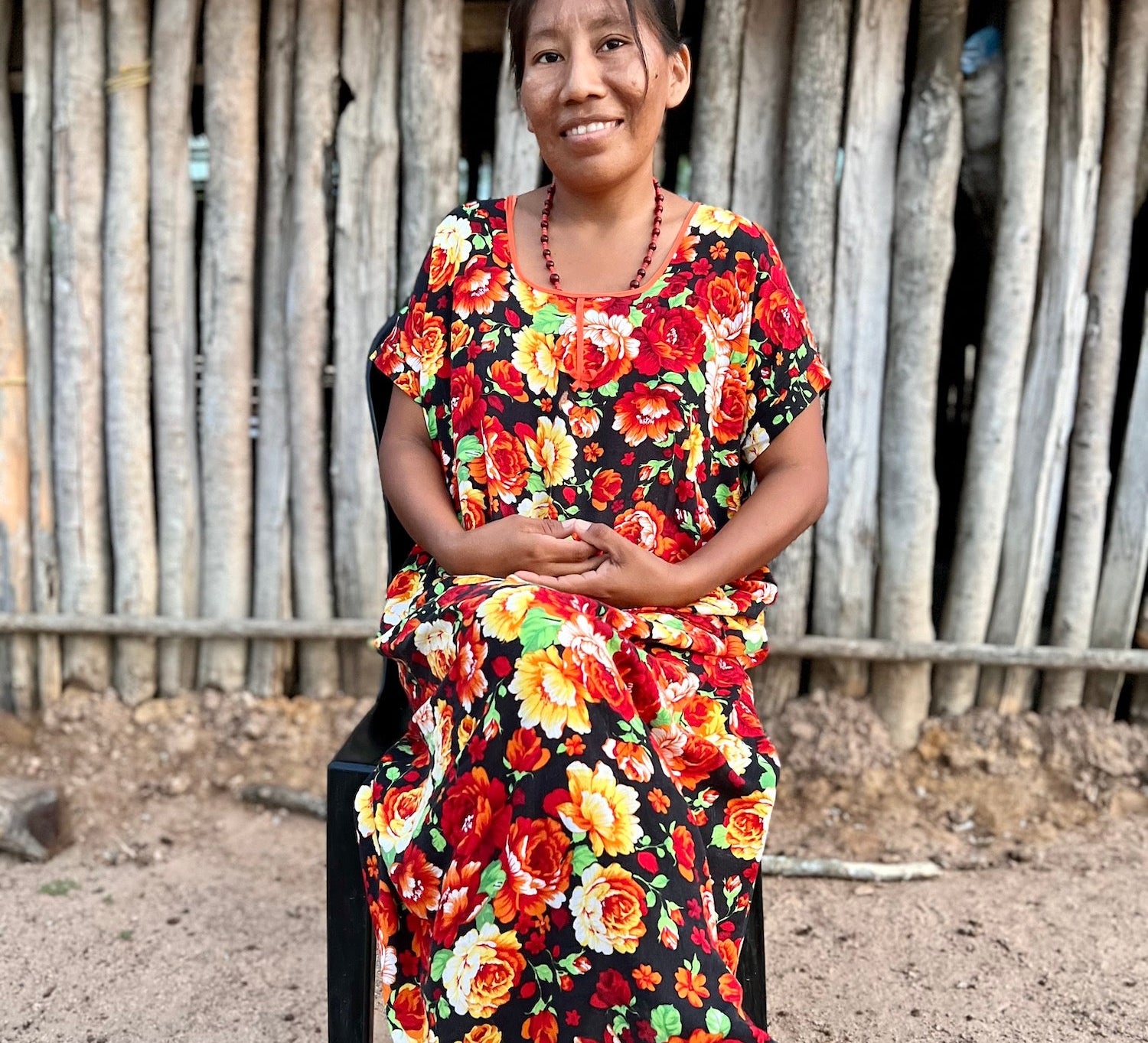 Wayuu woman sitting in from of her home in colourful "manta" dress 