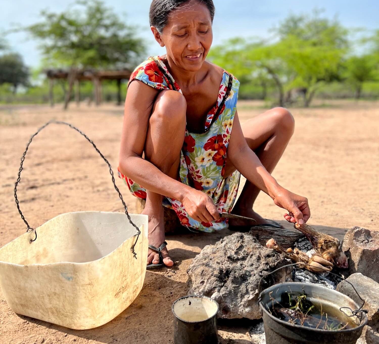 Wayuu woman cooking on a traditional "llana" outdoor coal stove 