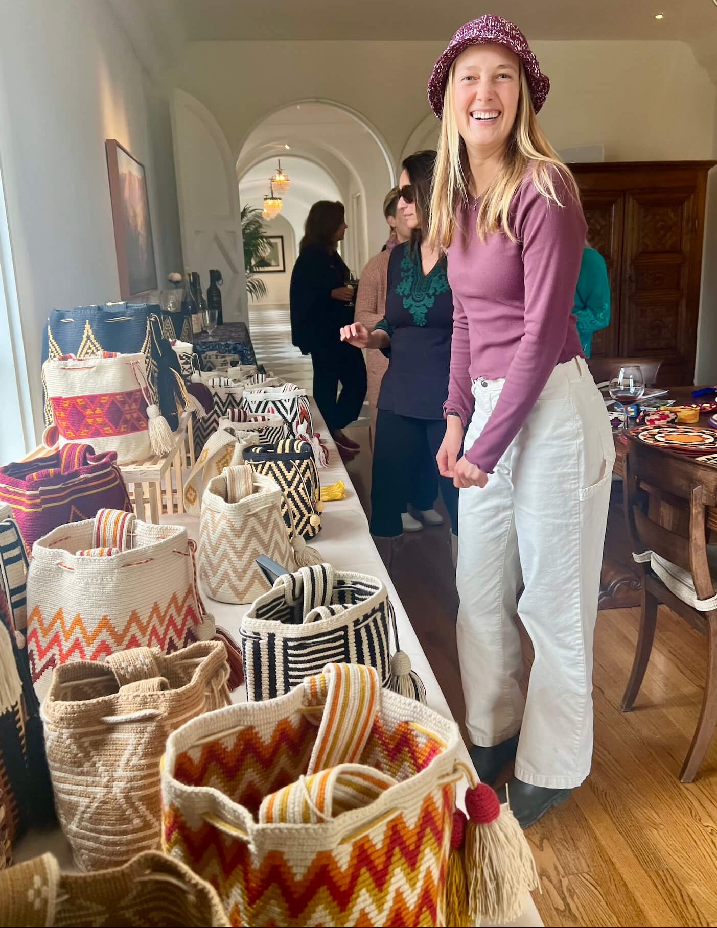 Woman standing in a room with colorful bags and people in the background